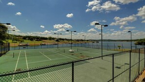 An outdoor tennis court with a chain-link fence, surrounded by a body of water and trees. - Lake View - Gorgeous Lake Travis Island Condo!!! (Lago Vista)