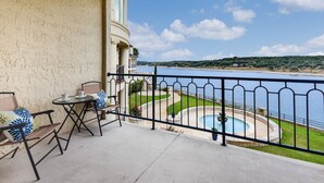 A balcony with a view of a lake, a pool, and a landscaped area. - Lake View - Gorgeous Lake Travis Island Condo!!! (Lago Vista)