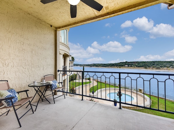 Un balcón con vista a un lago, una piscina y una zona ajardinada.