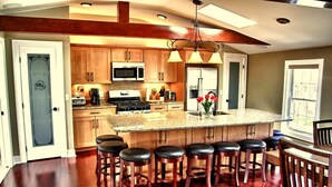 A spacious kitchen with wooden cabinets, a large island with bar stools, and a central island with a sink and countertop.