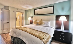 Una habitación de hotel con cama, mesitas de noche, un espejo y una puerta.