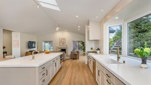 Una cocina moderna con armarios blancos, una isla grande y vistas al exterior a través de amplios ventanales.