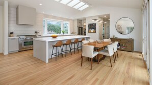 Una cocina moderna con una isla central, taburetes de bar y una mesa de comedor con sillas.