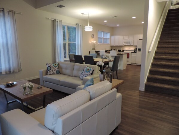 A modern living room with a sofa, coffee table, and dining area.