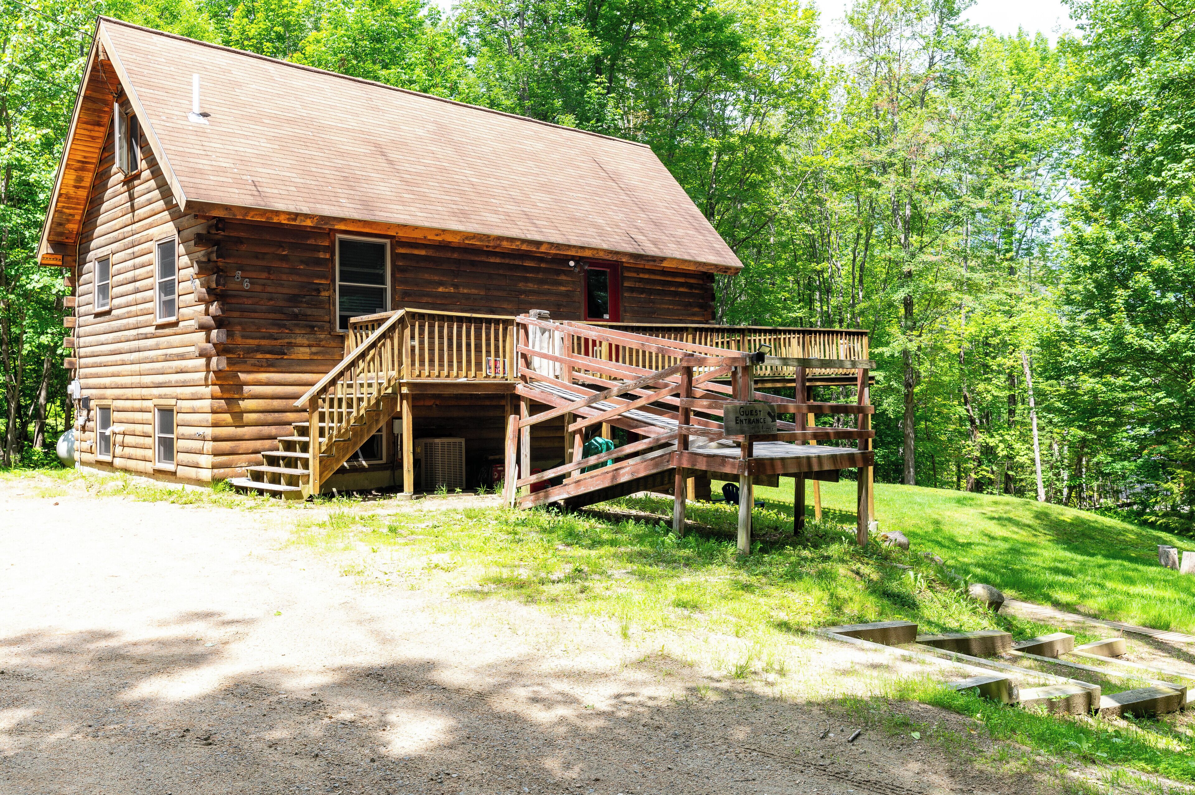 A log cabin with a wooden deck and a staircase leading to a porch.