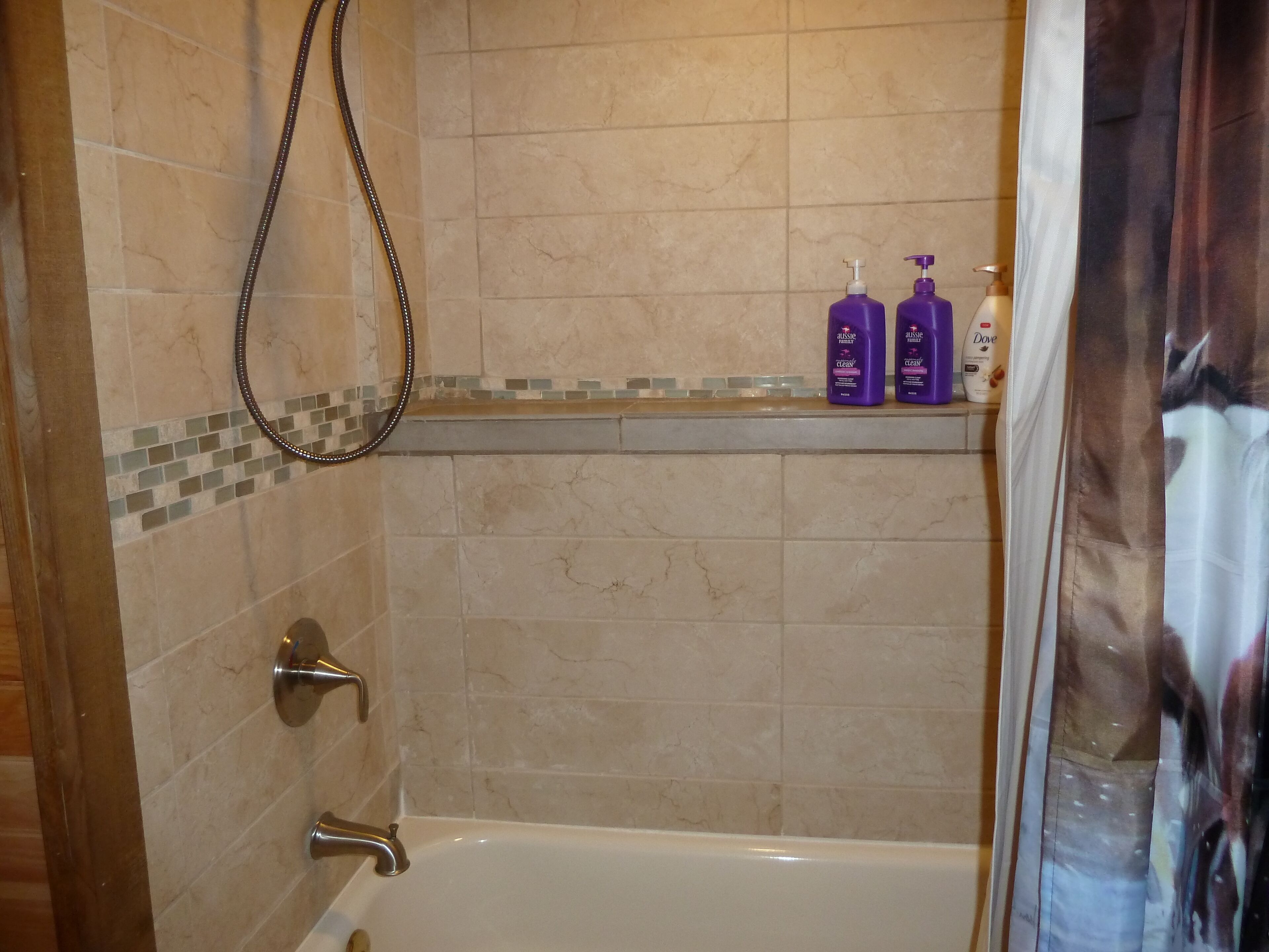 Un bagno con una vasca, un soffione doccia e uno scaffale con articoli da toilette.