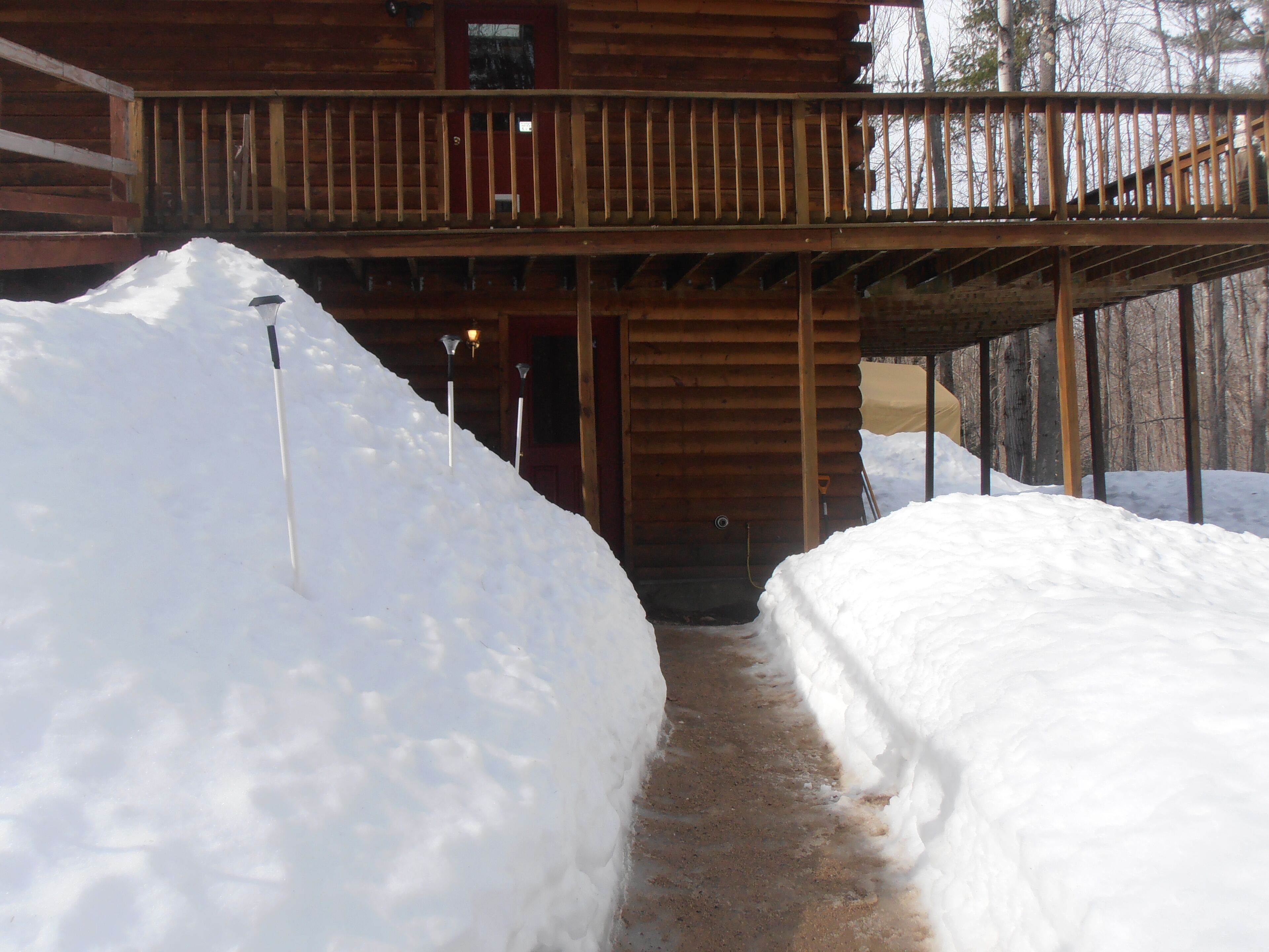 A wooden cabin with a covered porch and a snow-covered path leading to the entrance.
