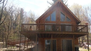 Eine zweistöckige Holzhütte mit Balkon, umgeben von Bäumen.