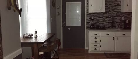 Una cocina compacta con comedor, un refrigerador pequeño y un microondas.