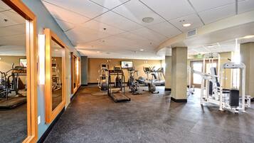 A spacious gym with various exercise equipment, including treadmills, elliptical machines, and weight machines.