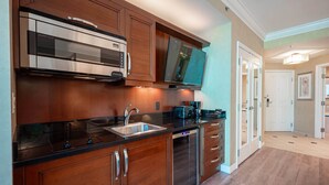 A modern kitchen with wooden cabinets, stainless steel appliances, and a walk-in refrigerator.