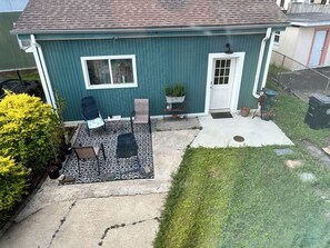 Ein Haus mit überdachter Terrasse, Eingangstür und einem kleinen Garten.