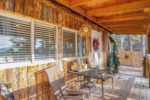 A wooden deck with a covered seating area, a decorative wreath, and a star decoration on the wall.