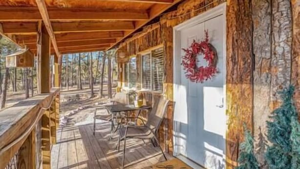 Een houten chalet met een veranda, een eettafel en stoelen.
