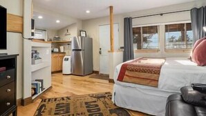 Een moderne hotelkamer met een bed, een bureau, een koelkast en een raam met gordijnen.