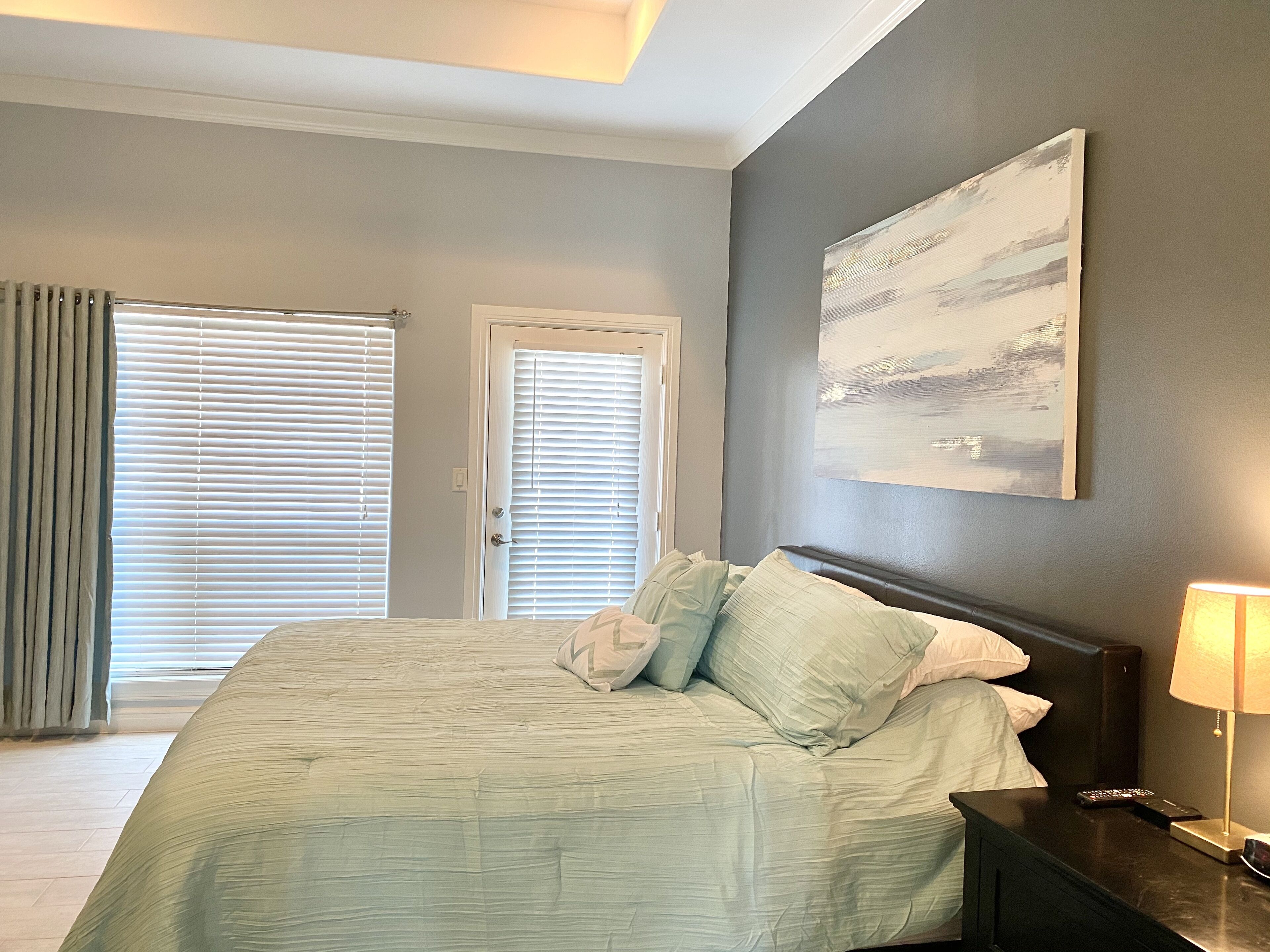 A bedroom with a bed, a nightstand, a lamp, and a painting on the wall.