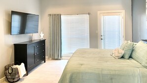 A bedroom with a bed, a dresser, a TV, and two windows with blinds. - BEAUTIFUL 3BR TOWNHOUSE w/ POOL and JACUZZI STEPS FROM BEACH - BOOK NOW! (South Padre Island)