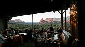A restaurant with patrons dining inside, overlooking a mountainous landscape through large windows. - Luxurious, Upscale Townhome In Sedona. Super clean, gourmet kitchen, comfy beds! (Sedona)