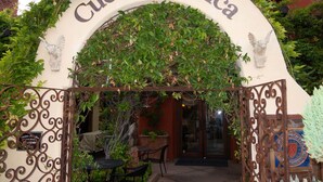 An entrance to Cucina Rustica with an arched sign, outdoor seating, and a decorative metal gate. - Luxurious, Upscale Townhome In Sedona. Super clean, gourmet kitchen, comfy beds! (Sedona)