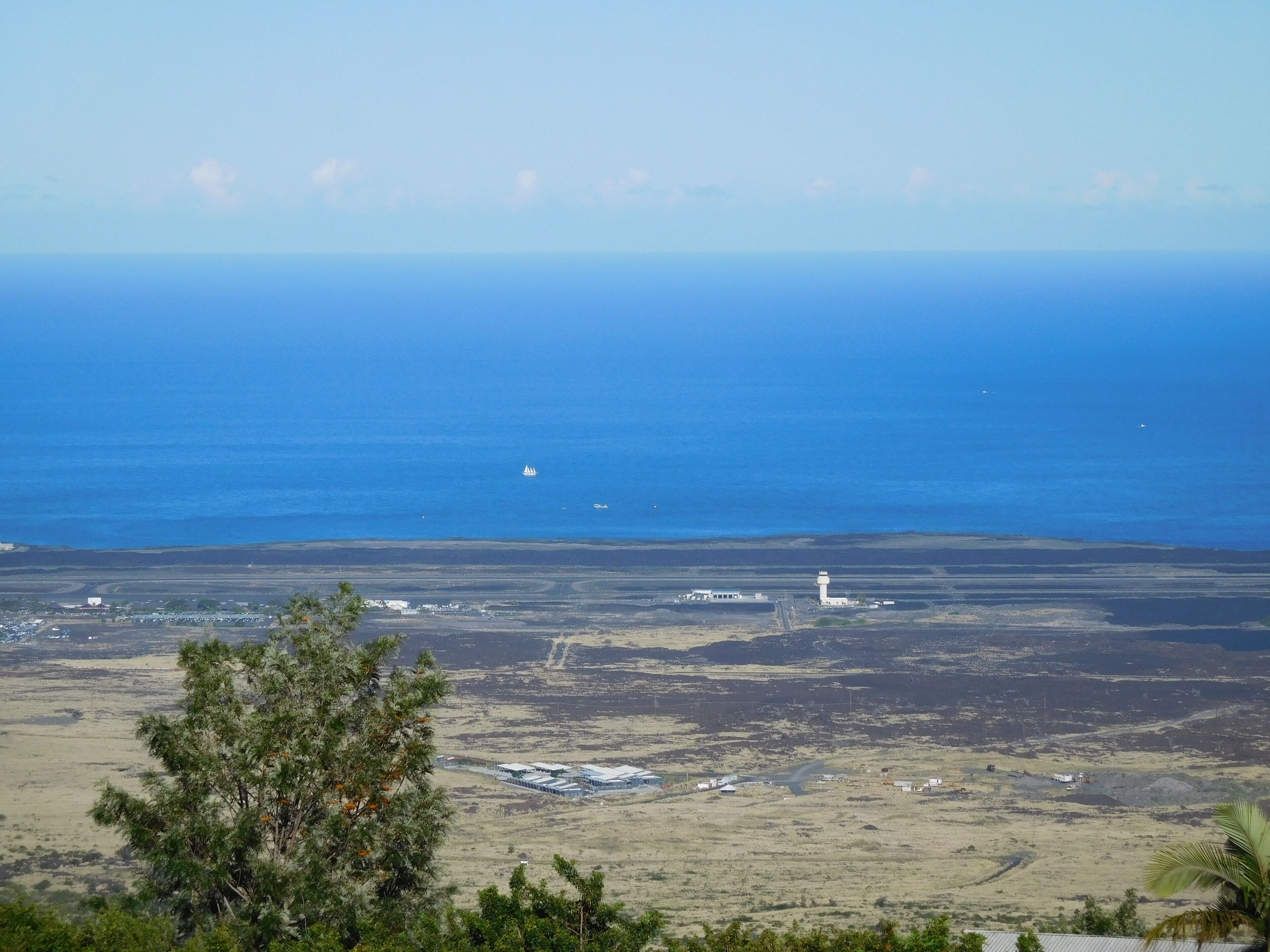 A coastal landscape with a lighthouse, open fields, and a distant ship.