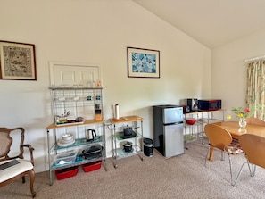 A compact kitchen with a refrigerator, microwave, and various kitchenware on shelves. - Beautiful, Ocean View Studio- Quiet, Kitchenette, Sleeps 4, Free WiFi & Parking (Kailua Kona)