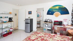 A compact kitchen with a refrigerator, microwave, and toaster. A dining area with a table and chairs is visible.