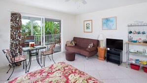 A living room with a sofa, TV, and a dining area with chairs and a table.