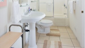 A modern bathroom with a white sink, toilet, and shower. There is a glass shower enclosure, a towel rack, and a mirror above the sink.