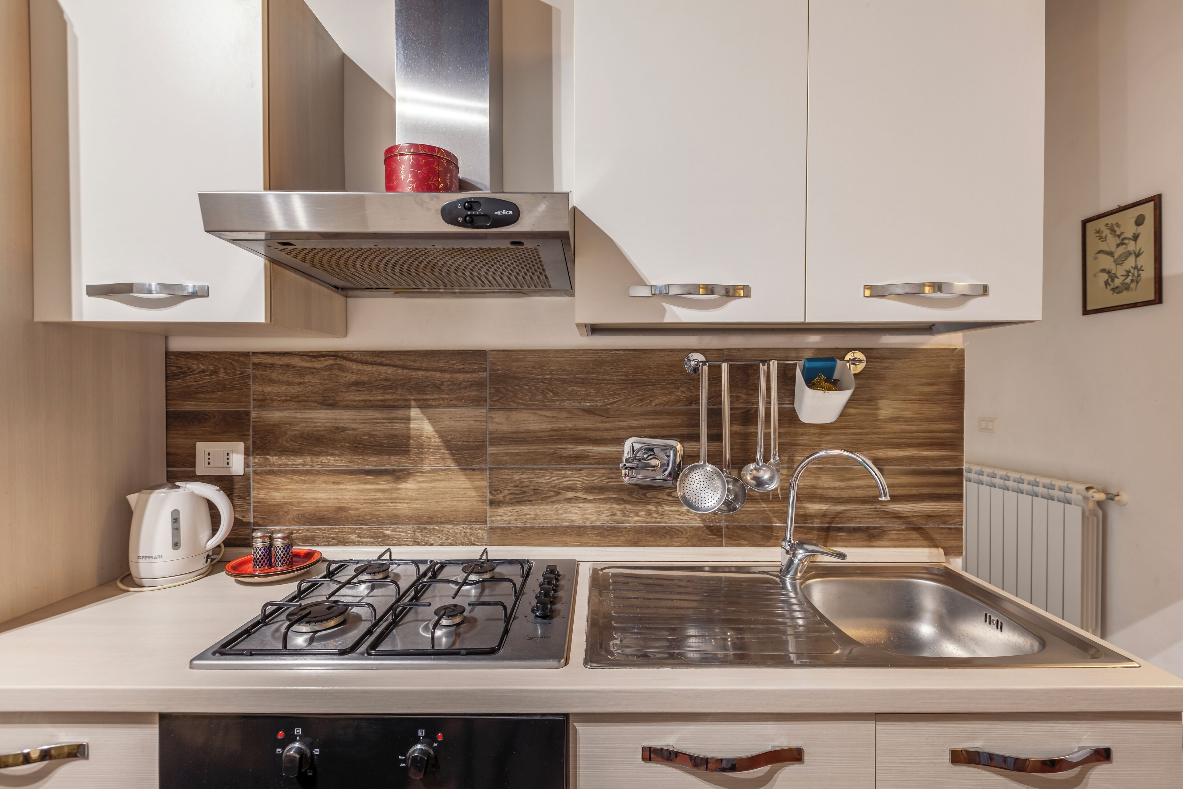 A modern kitchen with a gas stove, stainless steel sink, and wooden backsplash.