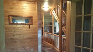 A wooden interior with a staircase, a mirror on the wall, and a bench.