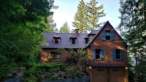 A two-story house with a brick facade, a steeply pitched roof, and a gravel driveway. - On The Beach! Elegant Waterfront Manor 'The Pearl on Oyster Bay (Bremerton)