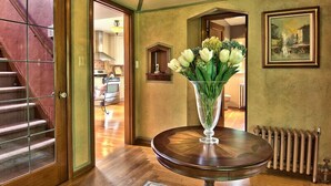 A room with a wooden staircase, a round table with a vase of flowers, and a framed picture on the wall. - On The Beach! Elegant Waterfront Manor 'The Pearl on Oyster Bay (Bremerton)