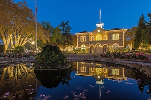 A historic building with a pond and illuminated trees.