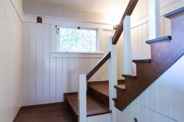 A wooden staircase with white paneling and a window above.
