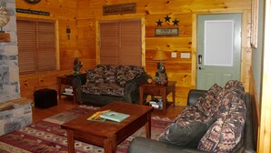 L’intérieur d’un chalet confortable, avec un canapé à motifs, une table basse en bois et une cheminée.