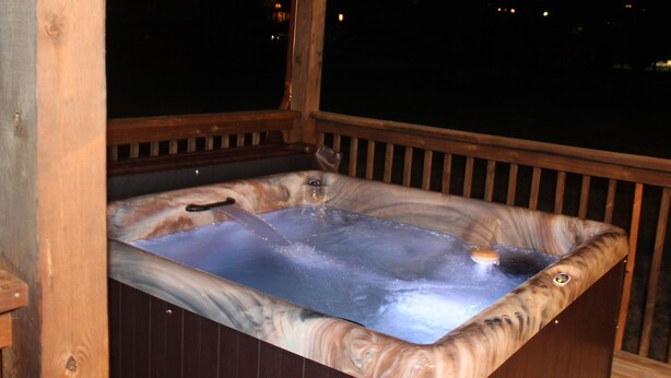 Un bain à remous avec une terrasse en bois et une vue sur le ciel nocturne.
