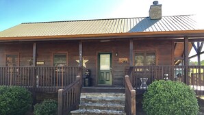 Un bâtiment rustique en bois, doté d’une porte verte, d’un escalier en pierre et d’un toit en métal.