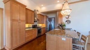 A kitchen with wooden cabinets, stainless steel appliances, a granite countertop, and a chandelier.