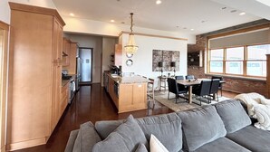 A spacious kitchen with wooden cabinets, a dining area with a chandelier, and a large window providing natural light.