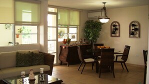Una sala de estar con sofá, mesa de centro, mesa de comedor, sillas y un ventanal grande.