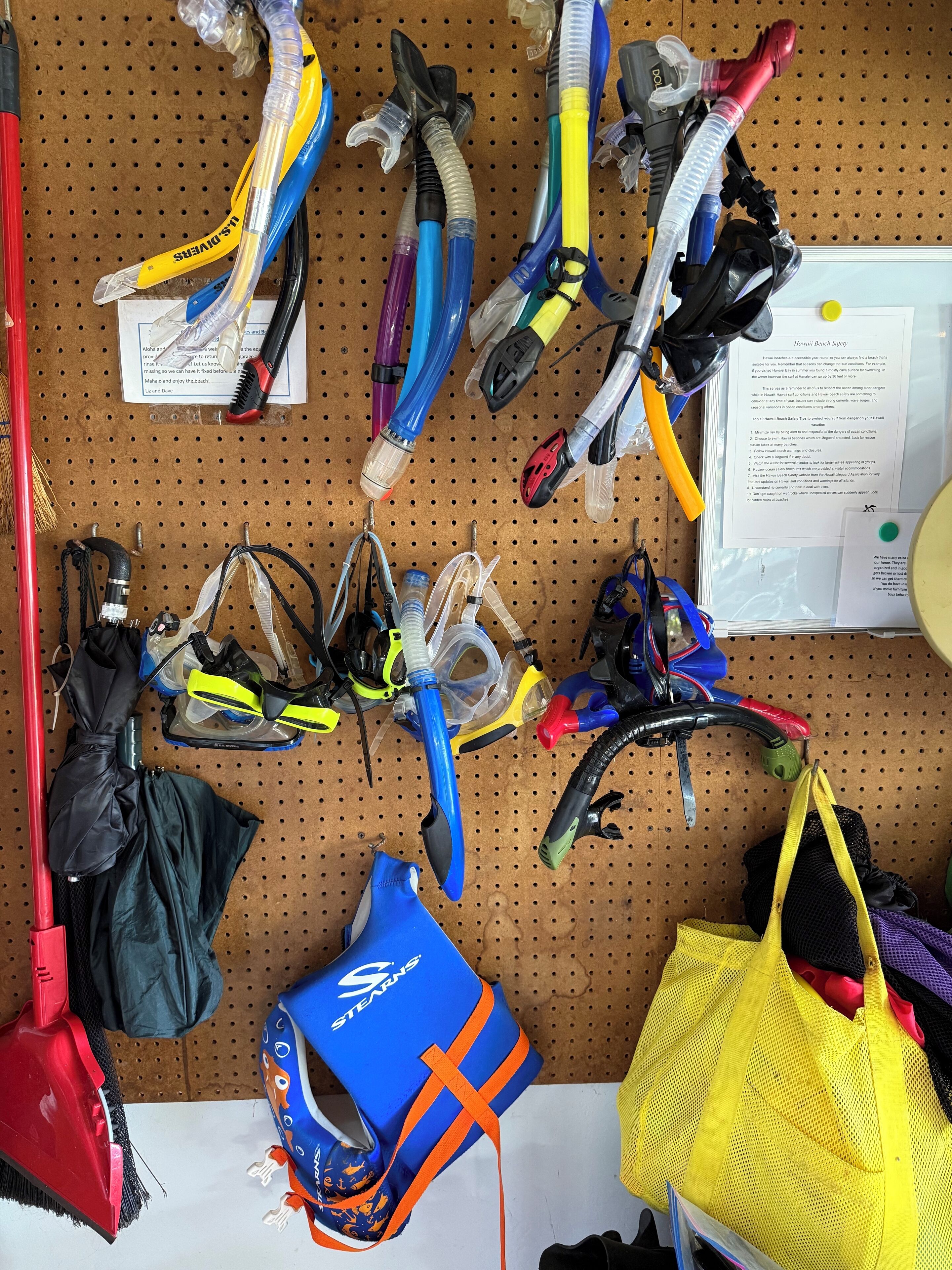 Un panel de usos múltiples con diverso equipo de buceo y snorkel, incluyendo máscaras, tubos de respiración y aletas, además de bolsas y una botella de agua azul.