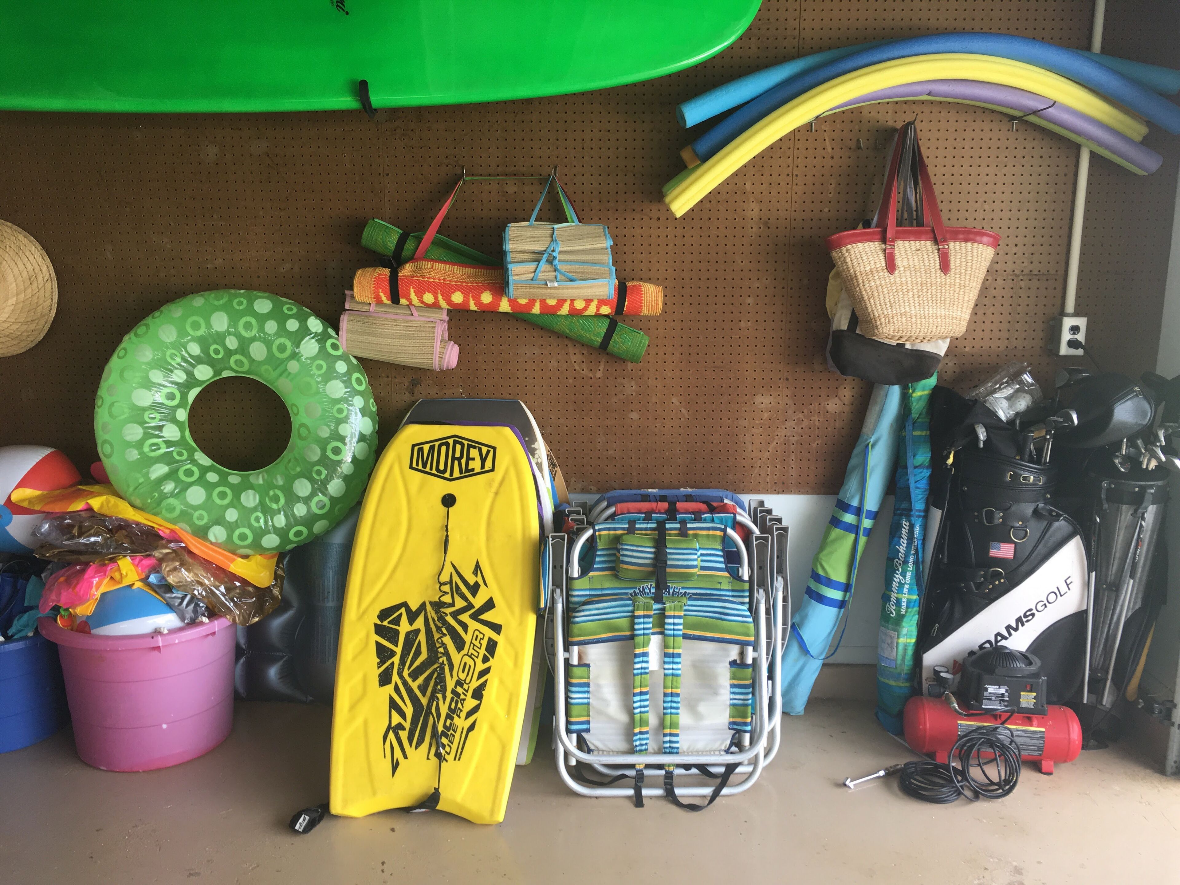 A storage area with various items including a yellow Morey brand bag, a green inflatable ring, a pink bucket, and a golf cart.