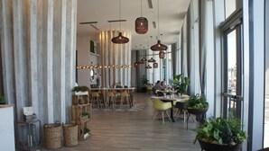 Un restaurant spacieux avec de hauts plafonds, des luminaires suspendus et différents types d’aménagements pour s’asseoir.