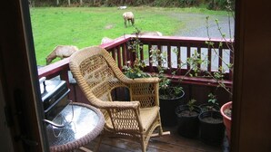 A wicker chair and a small table on a wooden deck with potted plants. - Contemporary farmhouse in Redwood National Park (Orick)