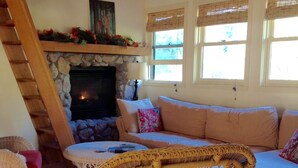 A cozy living room with a stone fireplace, a wicker chair, a sofa, and a television. - Contemporary farmhouse in Redwood National Park (Orick)