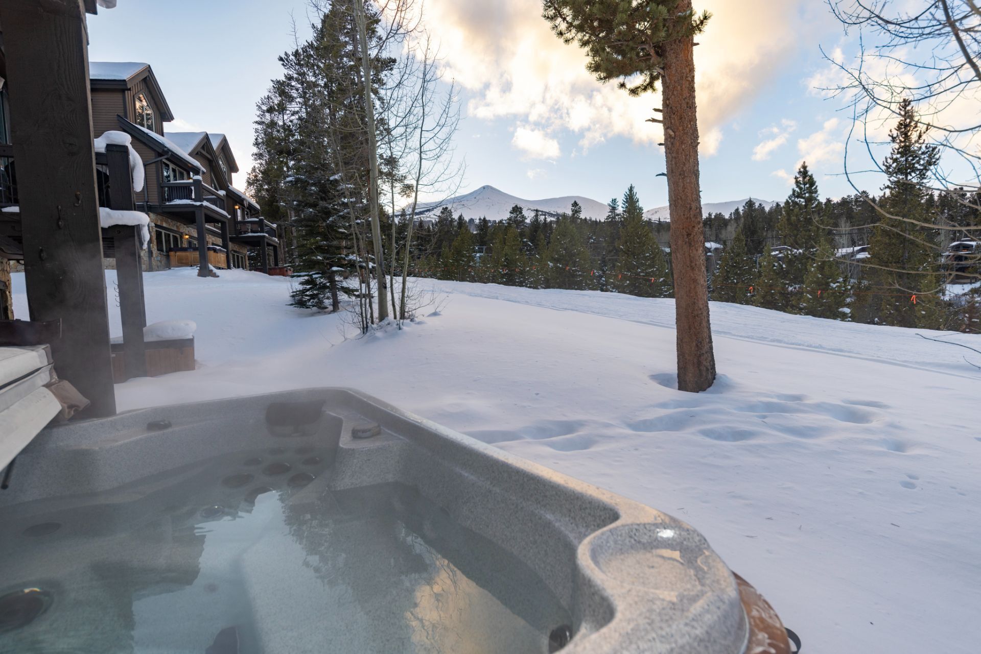 A hot tub in a snowy outdoor area with a mountain in the background.