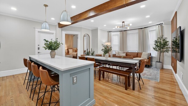 A modern kitchen with a central island, wooden flooring, and pendant lighting.