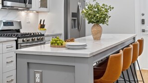 A modern kitchen with a central island, stainless steel appliances, and a potted plant.