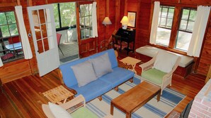 Ein gemütliches Blockhaushaus-Interieur mit einem blauen Sofa, einem Holztisch und einem Korbstuhl.