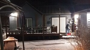 Sneetækt baghave med træterrasse, gyngestativ og et hus i baggrunden.